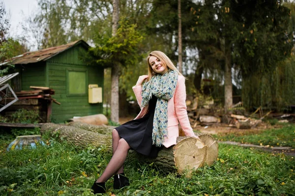 핑크 코트에서 젊은 금발 소녀에 앉아가 공원에 제기 — 스톡 사진