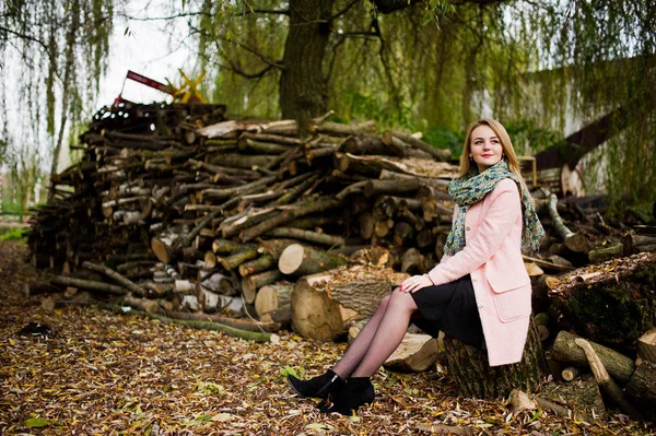 Jeune fille blonde à manteau rose posé contre souches en bois backg — Photo