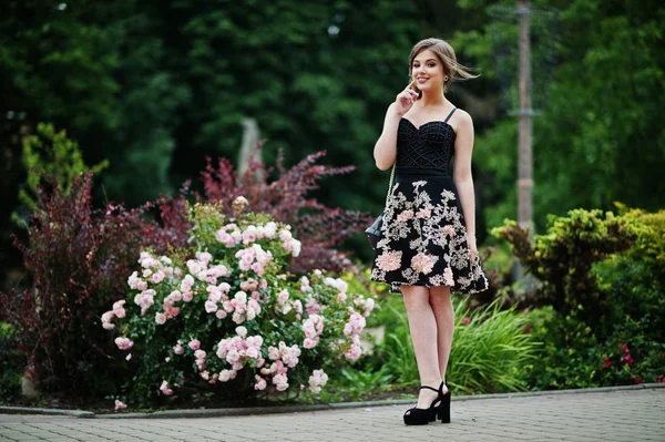 Portret van een prachtig meisje in zwarte bloemen jurk wandelen — Stockfoto