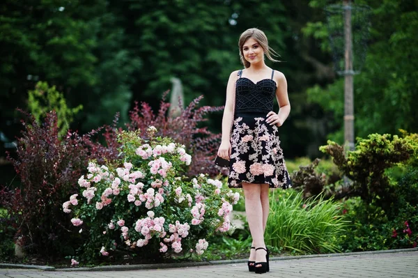 Portret van een prachtig meisje in zwarte bloemen jurk wandelen — Stockfoto