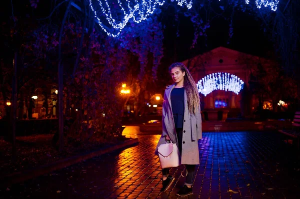 Дівчина з дредлоками ходить на нічній вулиці міста проти гар — стокове фото