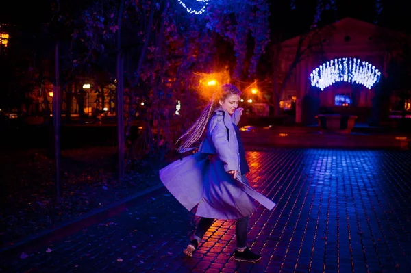Dziewczyna z dredami, chodzenie w nocy ulica miasta przeciwko gar — Zdjęcie stockowe