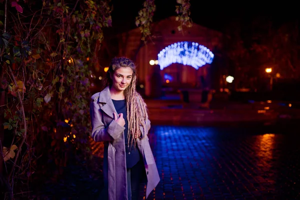 Дівчина з дредлоками ходить на нічній вулиці міста проти гар — стокове фото