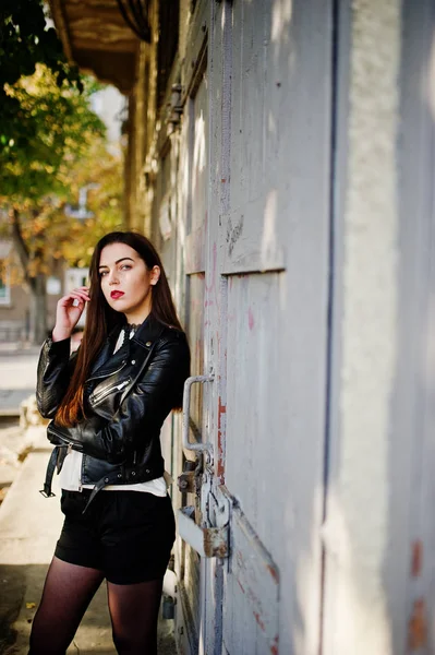 Elegante morena chica llevar en chaqueta de cuero y pantalones cortos posando un — Foto de Stock