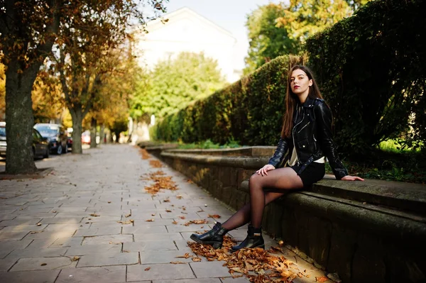Elegante chica morena usar en chaqueta de cuero y pantalones cortos sentados —  Fotos de Stock