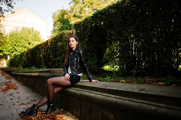 Elegante morena menina desgaste no couro jaqueta e shorts sentado — Fotografia de Stock