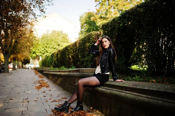 Elegante morena menina desgaste no couro jaqueta e shorts sentado — Fotografia de Stock