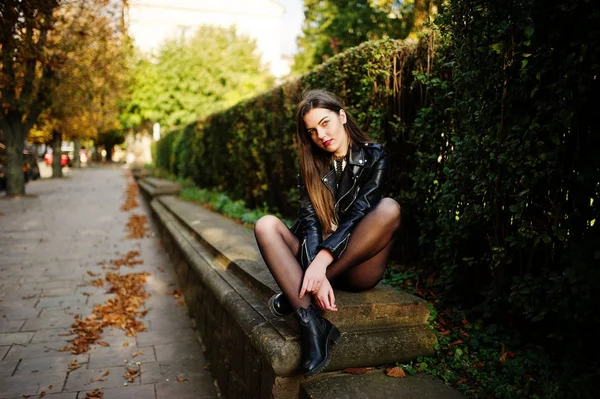 Elegante morena menina desgaste no couro jaqueta e shorts sentado — Fotografia de Stock