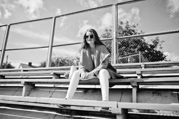 Flicka i grå kappa med solglasögon på lilla gatan stadion. — Stockfoto