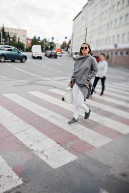 Güneş gözlüğü ve ped üzerinde yürüme çanta ile gri paltolu kız