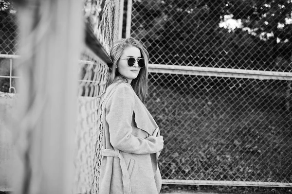 小さなストリート スタジアムでサングラスをかけたグレーのコートの女の子. — ストック写真