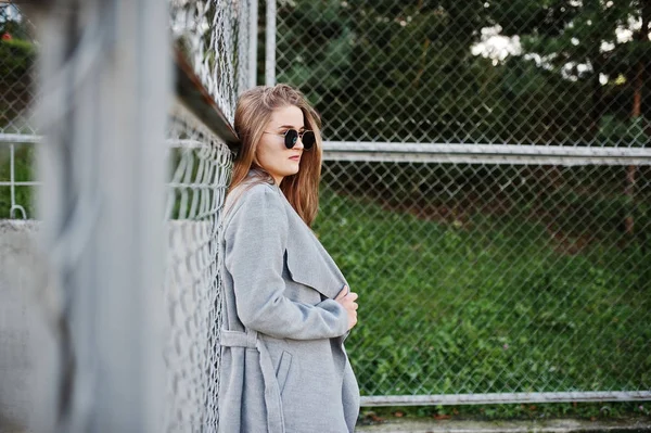 Flicka i grå kappa med solglasögon på lilla gatan stadion. — Stockfoto