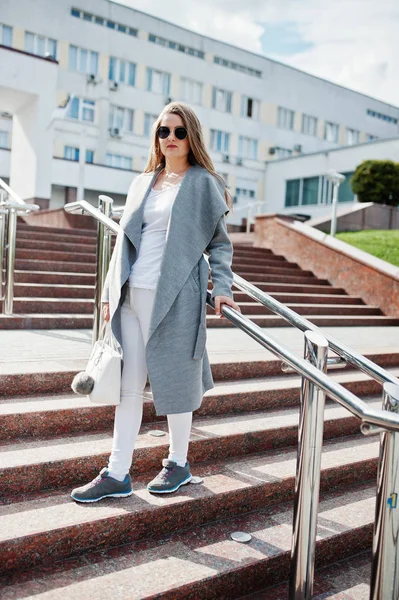 Chica de abrigo gris con gafas de sol y bolso de mano permanecer en las escaleras ingenio — Foto de Stock