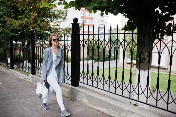 女孩在灰色外套与太阳镜和手提包在街道漫步 — 图库照片