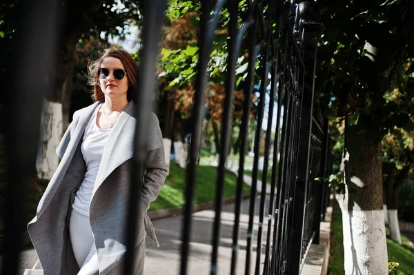 Menina de casaco cinza com óculos de sol e bolsa andando na rua — Fotografia de Stock