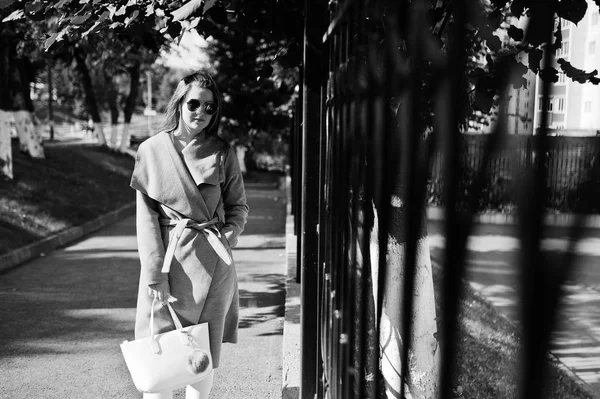 Mädchen im grauen Mantel mit Sonnenbrille und Handtasche läuft auf der Straße — Stockfoto