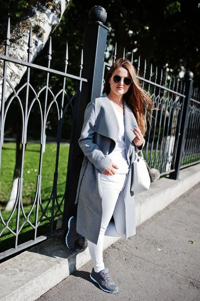 Mädchen im grauen Mantel mit Sonnenbrille und Handtasche läuft auf der Straße — Stockfoto