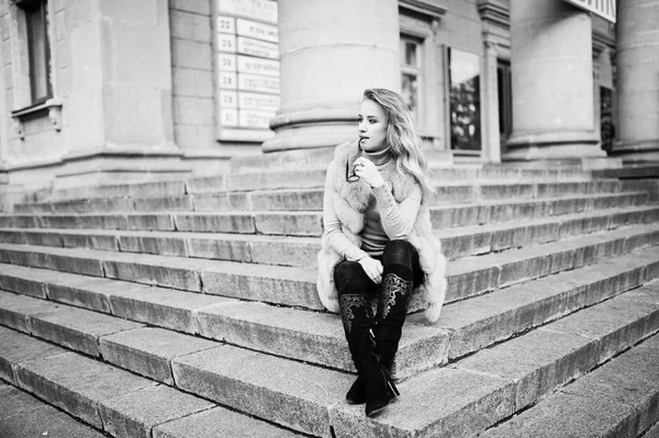 Blondes Mädchen mit Pelzmantel und Brille sitzt auf Treppe. — Stockfoto