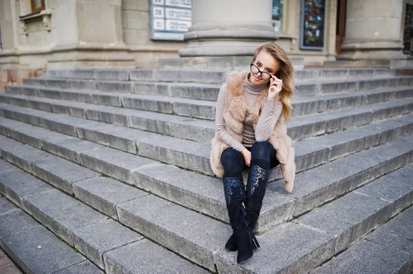 Blonde fille à fourrure manteau et lunettes assis sur les escaliers . — Photo