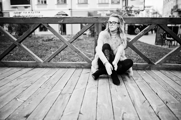 Ξανθιά κοπέλα στο γούνινο παλτό που κάθεται σε εξωτερική ξύλινο πάτωμα. — Φωτογραφία Αρχείου
