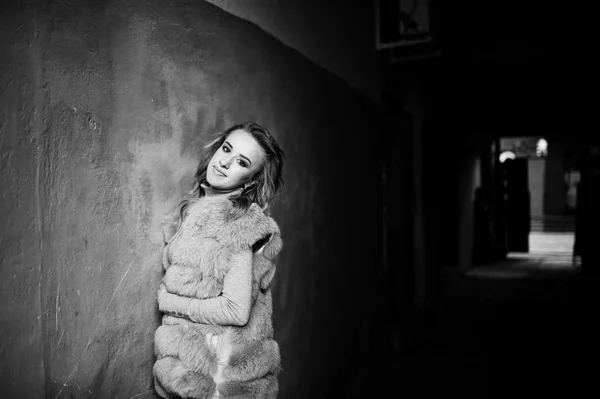 Chica rubia en abrigo de piel posado contra la vieja pared naranja . —  Fotos de Stock