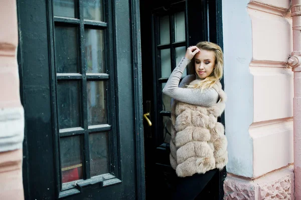 Blonde fille à fourrure manteau posé contre la vieille porte en bois . — Photo