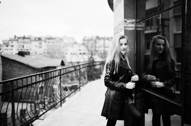 Uzun siyah deri montlu sarışın moda kız karşı poz verdi