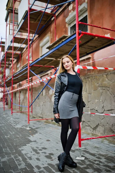 Blond fashionabla flicka i lång svart läder kappa poserade på stre — Stockfoto