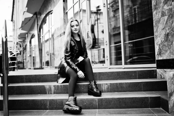 Blondes modisches Mädchen im langen schwarzen Ledermantel posierte am Stai — Stockfoto