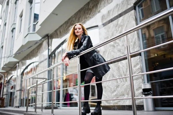 Blondes modisches Mädchen im langen schwarzen Ledermantel posierte beim Eisen — Stockfoto