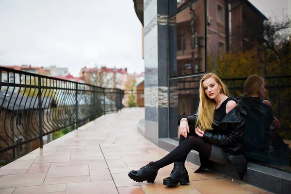Ξανθό κορίτσι της μόδας το μακρύ μαύρο παλτό από δέρμα που τίθεται κατά — Φωτογραφία Αρχείου