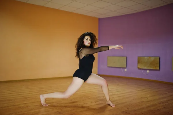 Morena rizada modelo de talla grande haciendo acrobacias en la sala de baile . — Foto de Stock