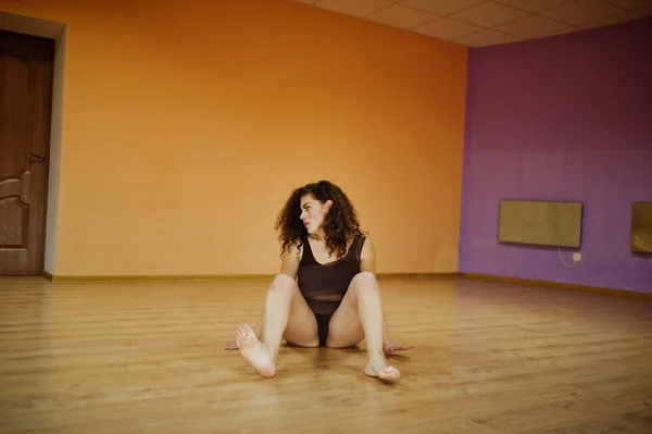 Kręcone brunetka plus rozmiar modelu robi akrobatyczne w sali tanecznej. — Zdjęcie stockowe
