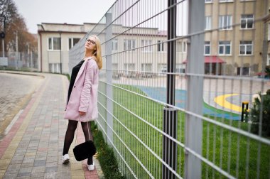 Gözlük ve pembe ceket, siyah tunik ve el çantası po sarışın kız