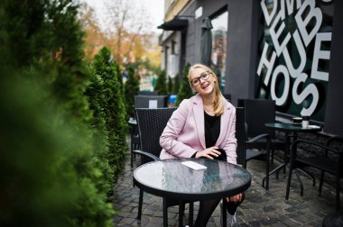 Sarışın kız gözlük ve pembe ceket, siyah sekmesini oturan tunik