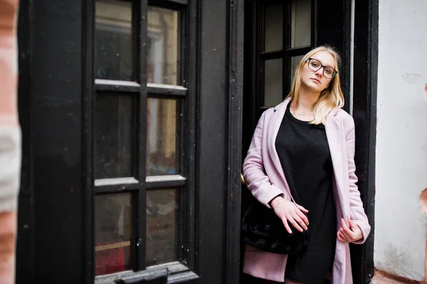 Blondes Mädchen mit Brille und rosa Mantel, schwarze Tunika gegen — Stockfoto