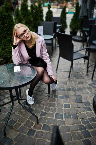 Blondes Mädchen mit Brille und rosa Mantel, schwarzer Tunika am Tab — Stockfoto