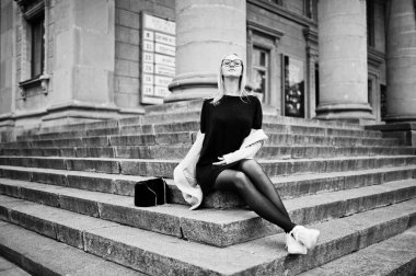 Sarışın kız sta üzerinde oturan çanta ile gözlük ve pembe ceket