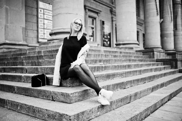 Blondes Mädchen mit Brille und rosa Mantel mit Handtasche auf dem Schoß — Stockfoto