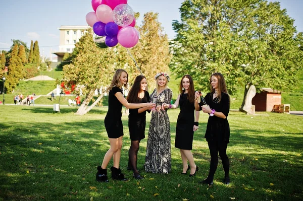 Cinco chicas se visten de negro con globos bebiendo champán rojo en — Foto de Stock