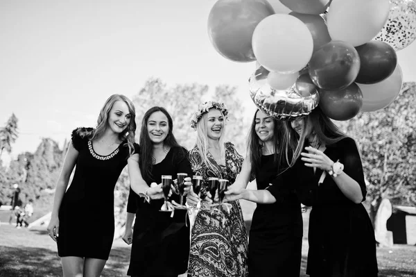 Five girls wear on black with balloons drinking red champagne at