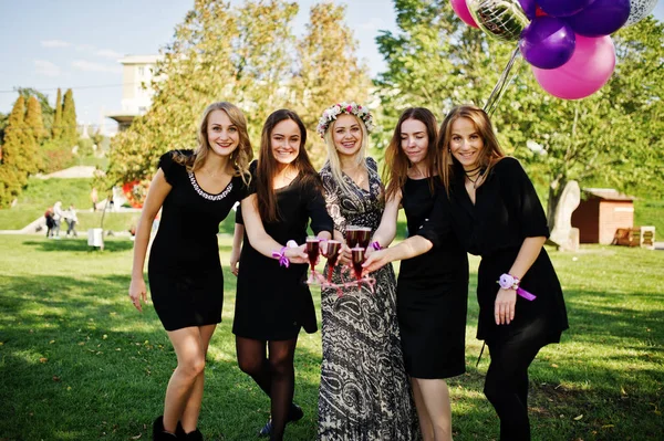 Fünf Mädchen tragen schwarz mit Luftballons, die roten Champagner trinken — Stockfoto