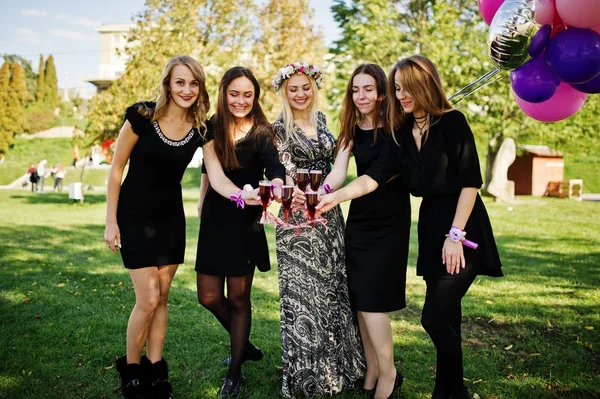 Fünf Mädchen tragen schwarz mit Luftballons, die roten Champagner trinken — Stockfoto