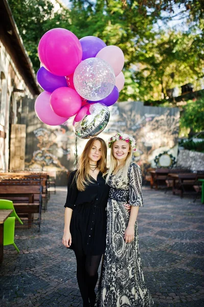 Twee meisjes dragen op zwart met ballonnen op kip feestje. — Stockfoto