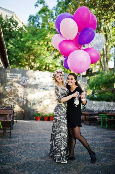 Twee meisjes dragen op zwart met ballonnen op kip feestje. — Stockfoto