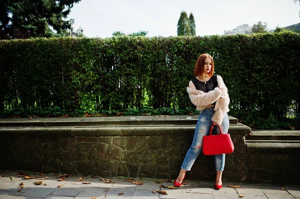 Fille aux cheveux rouges avec sac à main rouge posé à la rue de la ville . — Photo