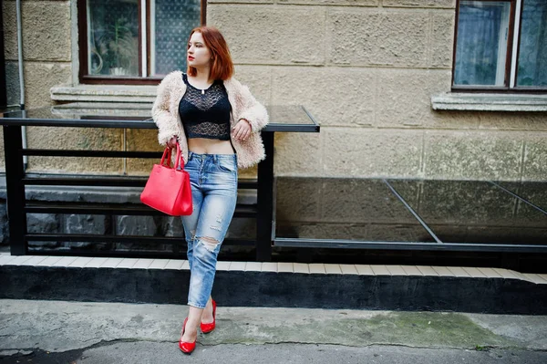 Fille aux cheveux rouges avec sac à main rouge posé à la rue de la ville . — Photo