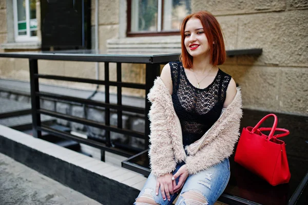 Fille aux cheveux rouges avec sac à main rouge posé à la rue de la ville . — Photo