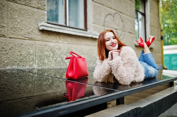 Menina de cabelos vermelhos com bolsa vermelha posou na rua da cidade . — Fotografia de Stock