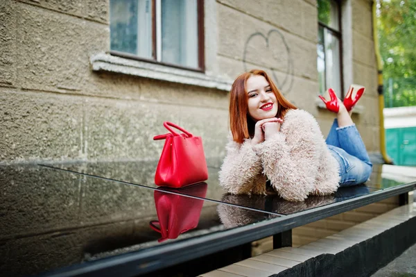 Fille aux cheveux rouges avec sac à main rouge posé à la rue de la ville . — Photo